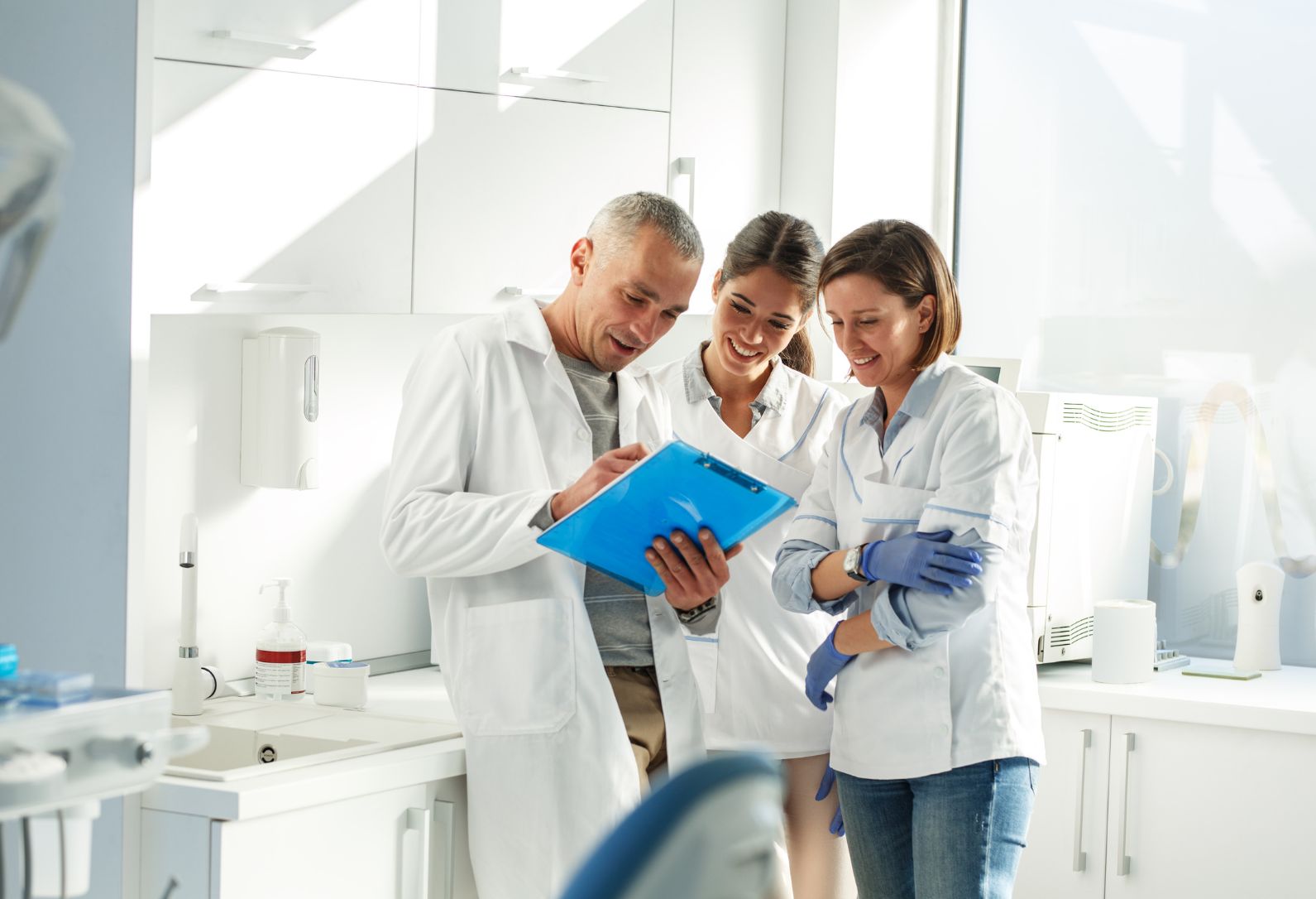 Three dentists huddled around a clipboard